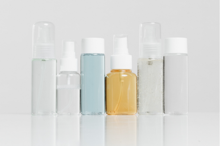Row of bottles of skincare products in plastic bottles, against a plain gray background.