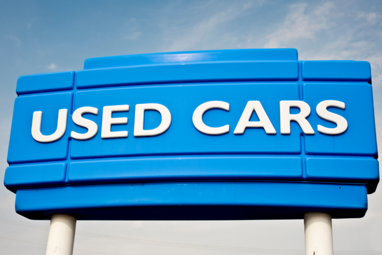Large sign displaying "Used Cars", against a blue sky