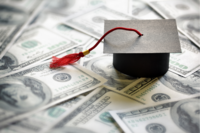 Image graduation cap on top of U.S. dollar bills.